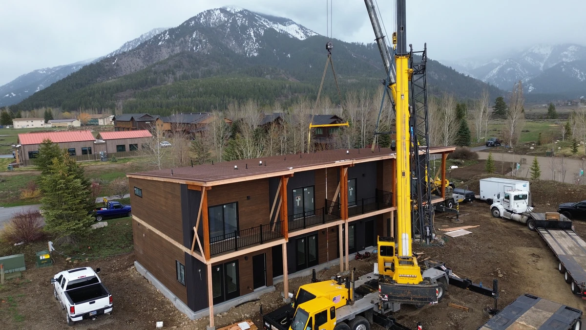 Crane setting the McKinley, a two-story modular building with balconies, in Alpine, Wyoming