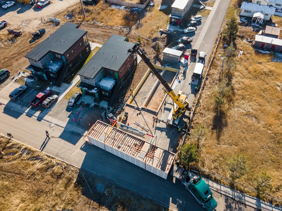 Aerial of a crane setting modules beside finished buildings at Westgroup in Victor, Idaho