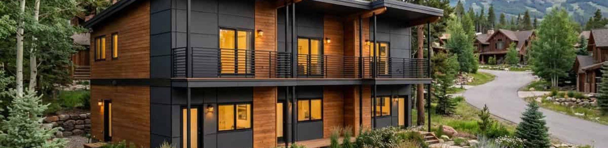 Modern Mckinley prefab home with black and wood exterior in mountain setting.